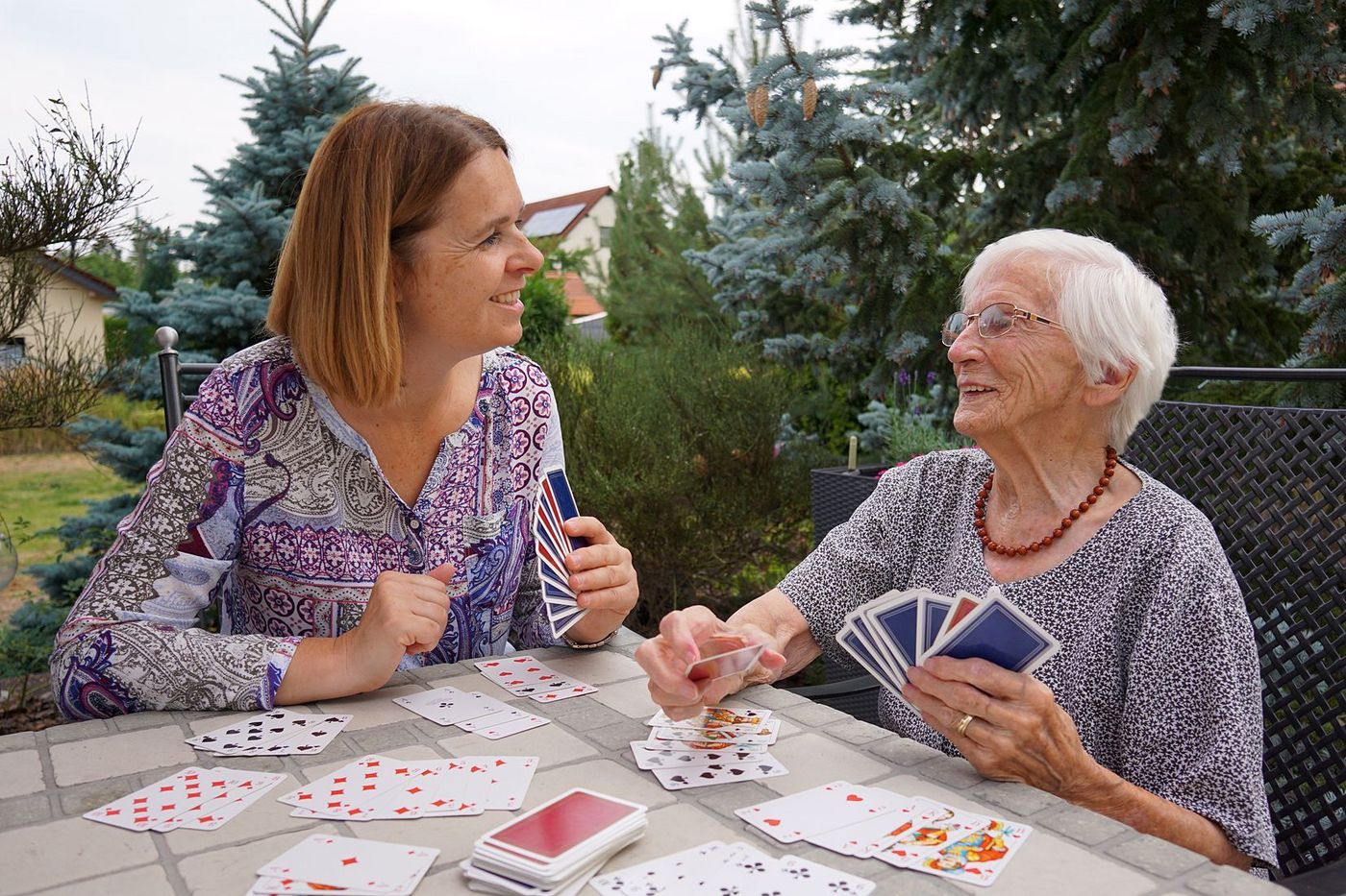Malteser Helferin spielt mit älterer Dame Karten